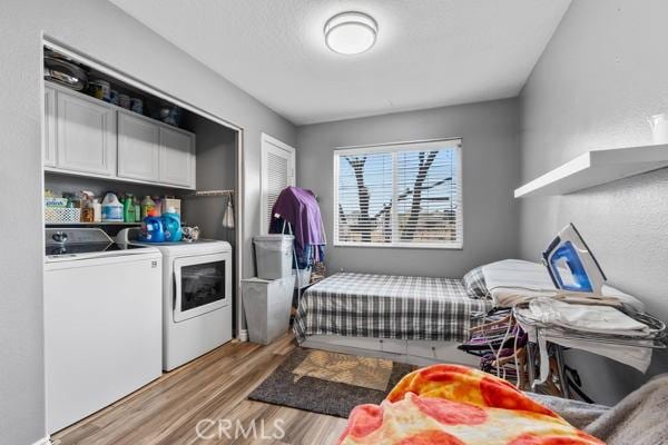 washroom with cabinet space, light wood-style floors, and independent washer and dryer