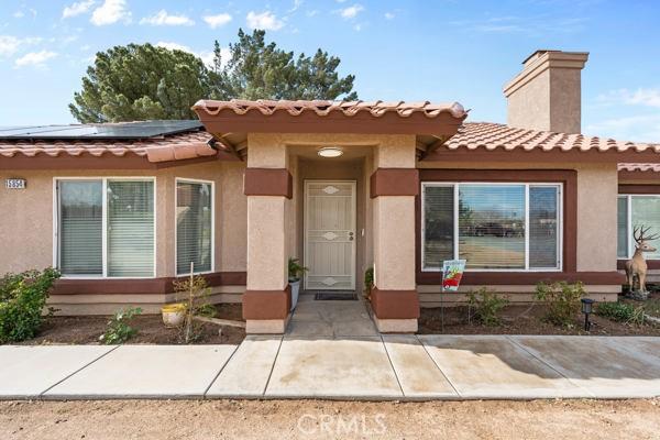 view of front of property featuring roof mounted solar panels, stucco siding, and a chimney