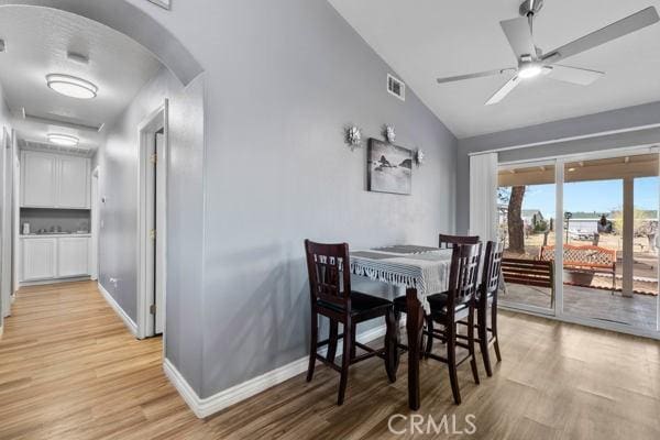 dining room with arched walkways, visible vents, light wood-type flooring, and ceiling fan