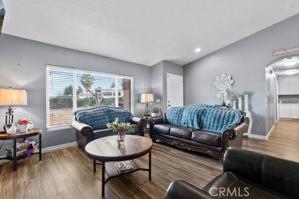 living area featuring arched walkways, baseboards, and wood finished floors