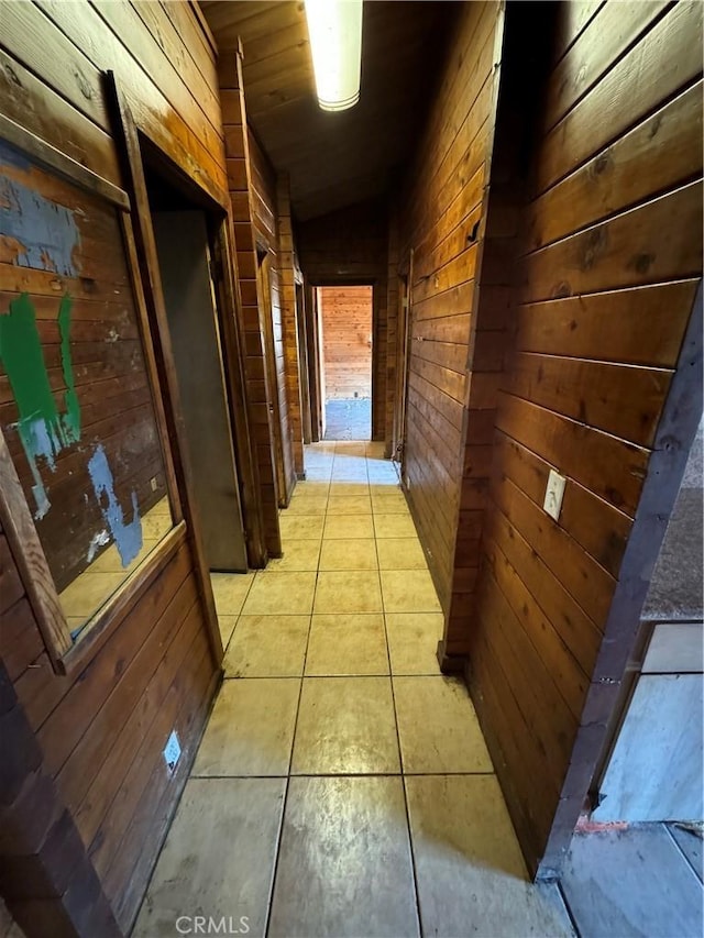 corridor with light tile patterned flooring and wooden walls