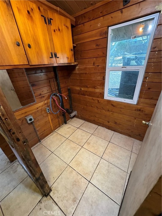 washroom featuring cabinet space, light tile patterned flooring, and wood walls