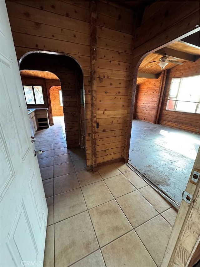 hallway with arched walkways, wooden walls, and a healthy amount of sunlight