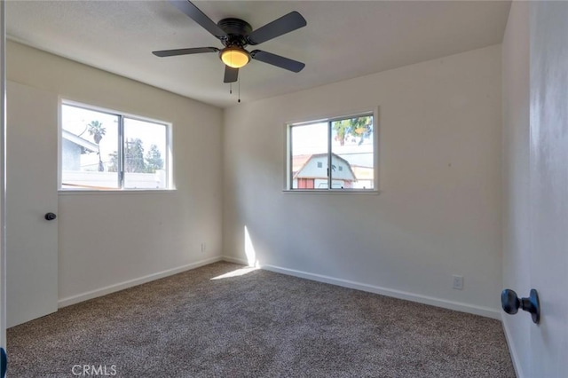 carpeted empty room with a ceiling fan and baseboards