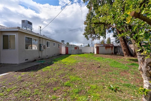 view of yard featuring a storage unit, an outdoor structure, cooling unit, and fence