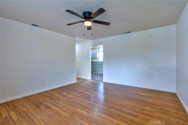 empty room featuring visible vents, baseboards, ceiling fan, and wood finished floors