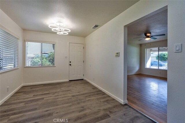 foyer featuring visible vents, ceiling fan with notable chandelier, baseboards, and wood finished floors