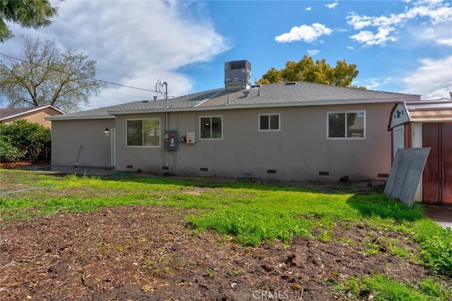 rear view of property with crawl space, a lawn, central AC, and a shingled roof