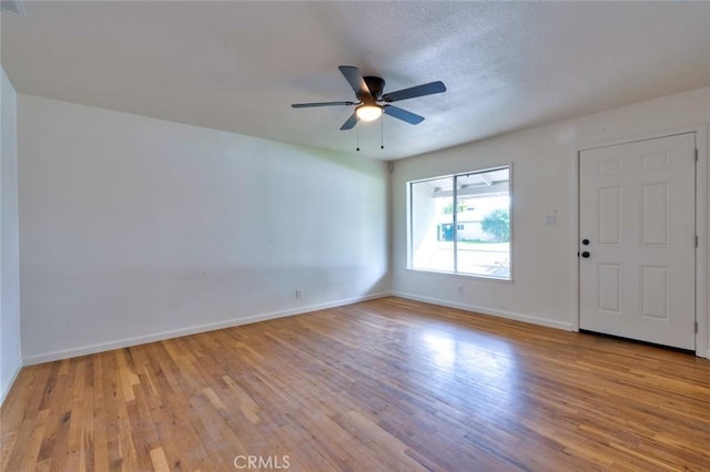 interior space featuring baseboards, a textured ceiling, wood finished floors, and a ceiling fan