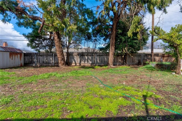 view of yard with an outbuilding, a storage shed, and a fenced backyard