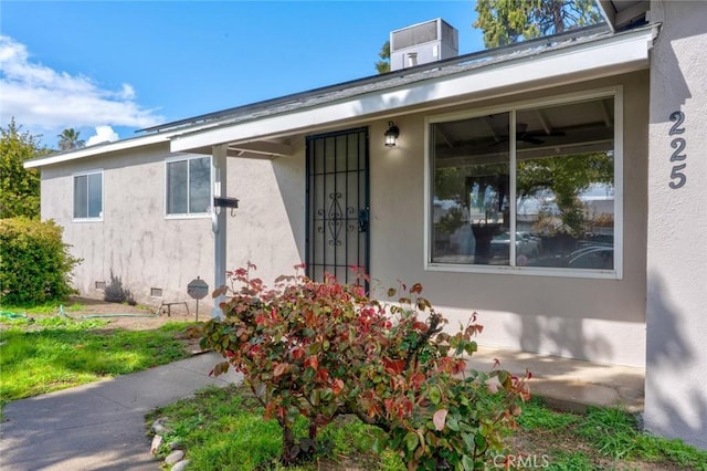 property entrance with crawl space, stucco siding, and central AC