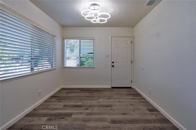 unfurnished dining area featuring visible vents, wood finished floors, baseboards, and a chandelier