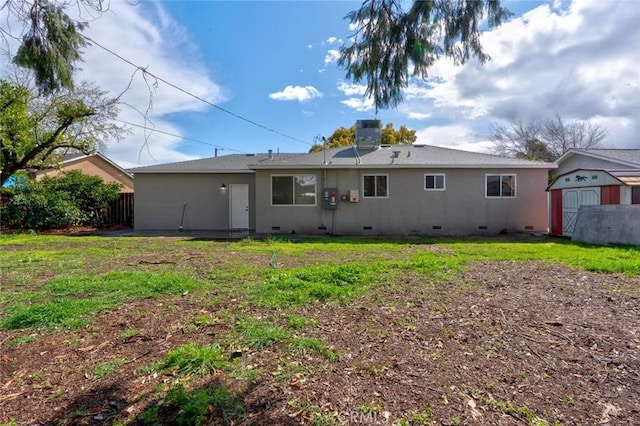 back of property featuring an outbuilding, fence, a shed, crawl space, and a lawn