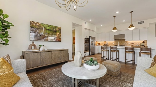 living room with recessed lighting, visible vents, dark wood-style flooring, and a chandelier