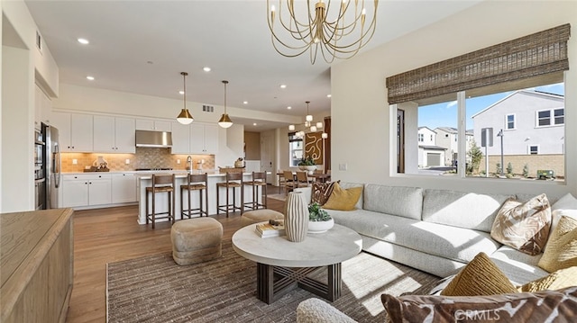 living area featuring recessed lighting, visible vents, an inviting chandelier, and wood finished floors