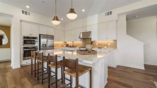 kitchen with under cabinet range hood, stainless steel appliances, visible vents, and a sink