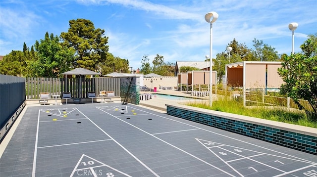 view of property's community with shuffleboard and fence