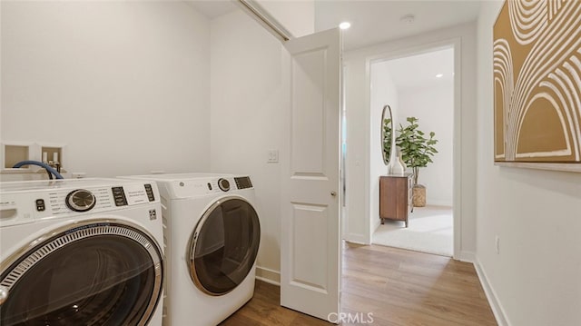 washroom featuring baseboards, light wood-style floors, laundry area, and washer and clothes dryer