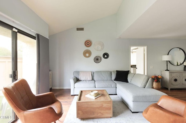 living room featuring visible vents, wood finished floors, baseboards, and vaulted ceiling