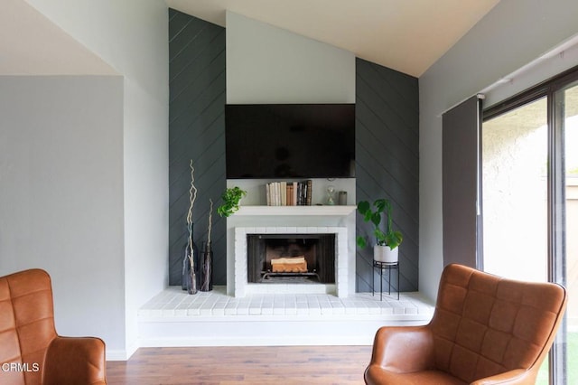 living room featuring a brick fireplace, wood finished floors, and baseboards