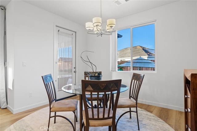 dining area featuring a chandelier, visible vents, baseboards, and wood finished floors