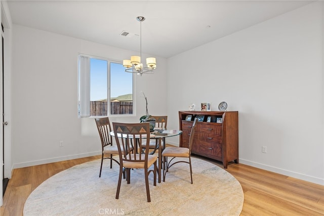 dining room featuring a notable chandelier, visible vents, light wood-type flooring, and baseboards