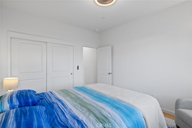 bedroom featuring wood finished floors, a closet, and baseboards