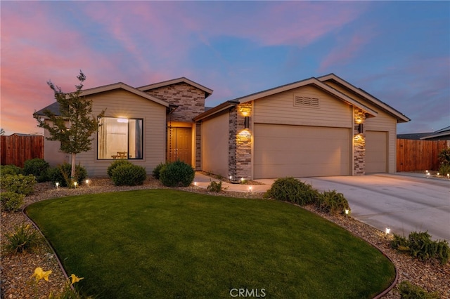 view of front of property with a front lawn, fence, concrete driveway, stone siding, and an attached garage