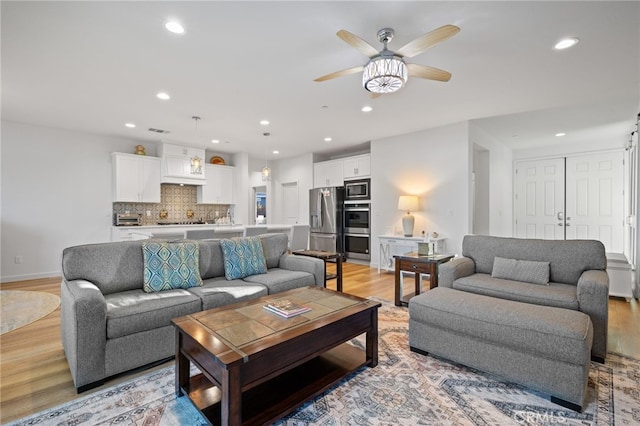 living room with visible vents, baseboards, ceiling fan, recessed lighting, and light wood-style flooring