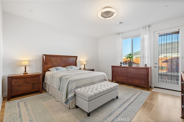 bedroom with visible vents, light wood-style floors, and access to outside