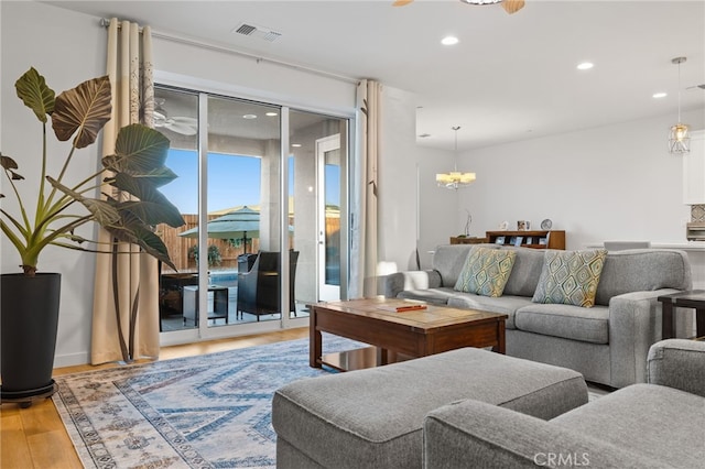 living room featuring recessed lighting, visible vents, wood finished floors, and ceiling fan with notable chandelier