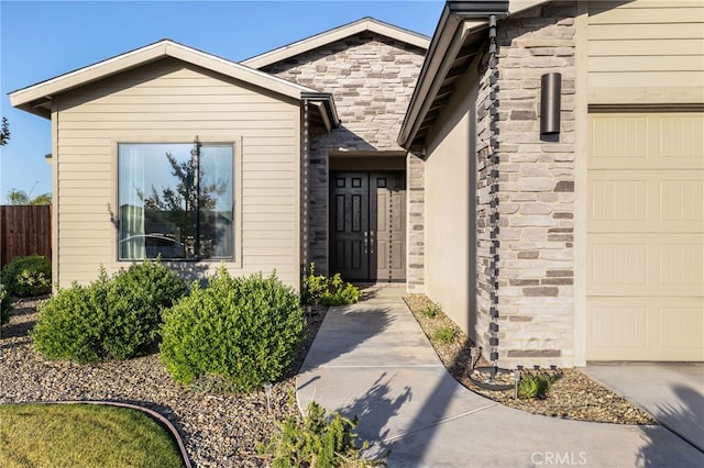 view of exterior entry featuring a garage, fence, and stone siding