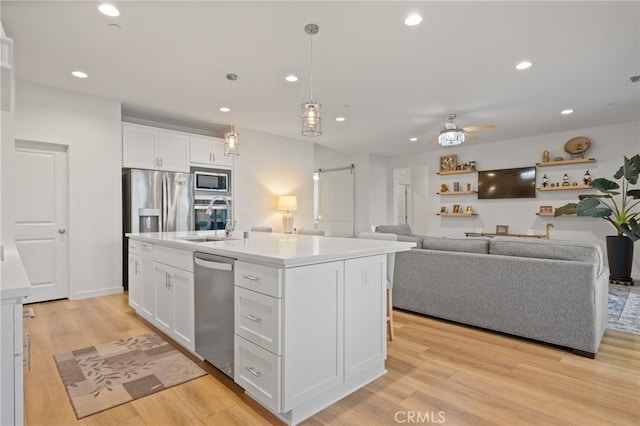 kitchen with white cabinets, appliances with stainless steel finishes, light wood-style floors, and a sink