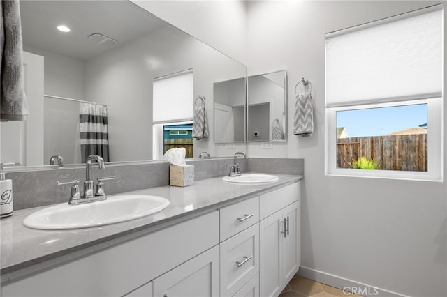 full bathroom featuring double vanity, baseboards, tile patterned floors, and a sink