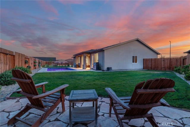 rear view of house with a fenced backyard, a patio area, stucco siding, and a yard