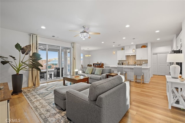 living room with recessed lighting, visible vents, ceiling fan with notable chandelier, and light wood finished floors