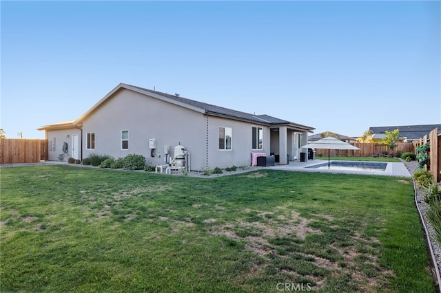 rear view of property with a yard, stucco siding, and a fenced backyard