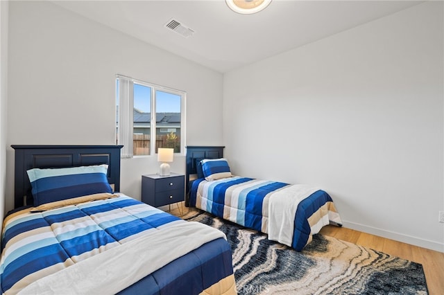 bedroom featuring visible vents, baseboards, and wood finished floors