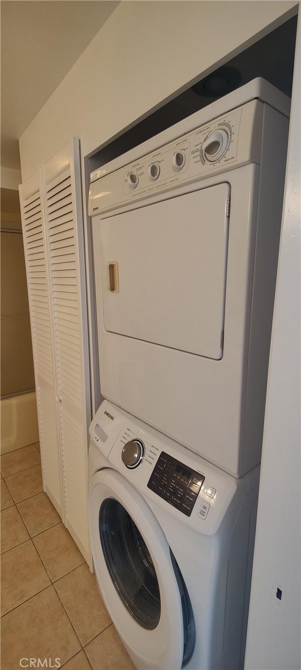 washroom with light tile patterned floors, laundry area, and stacked washer and dryer