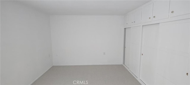 unfurnished bedroom featuring light carpet and baseboards