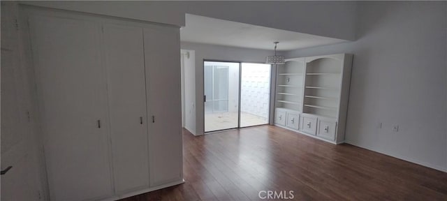 unfurnished bedroom with access to outside and dark wood-style flooring