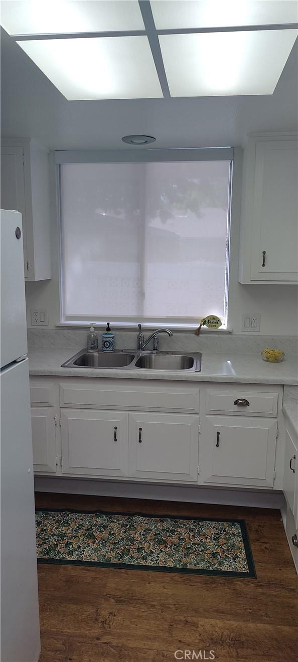 kitchen featuring a sink, white cabinetry, dark wood-style flooring, and freestanding refrigerator