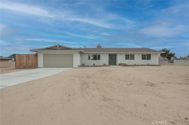 ranch-style house featuring concrete driveway, an attached garage, fence, and stucco siding