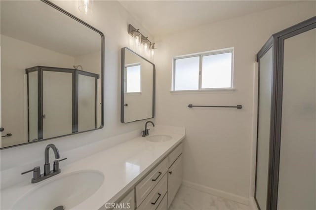 full bathroom with double vanity, a shower with shower door, baseboards, and a sink