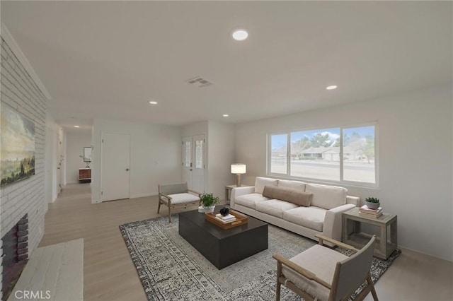 living area featuring a fireplace, light wood-style floors, recessed lighting, and visible vents