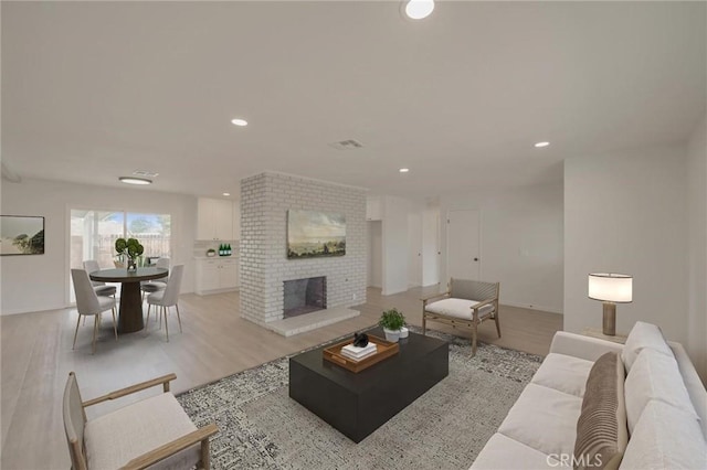 living area featuring light wood-style floors, a fireplace, visible vents, and recessed lighting
