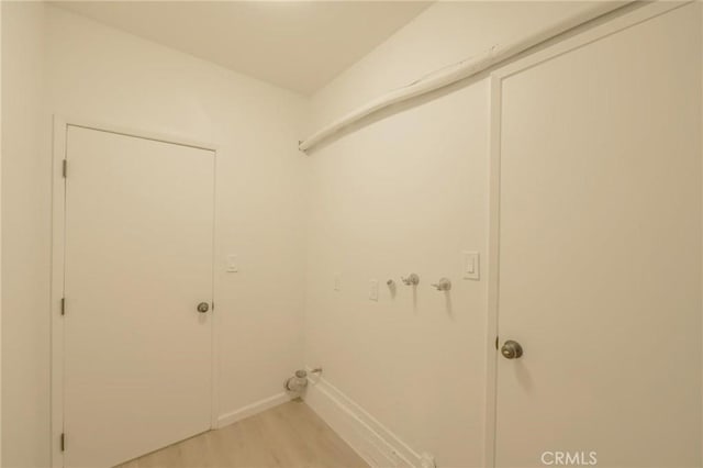 clothes washing area with light wood-type flooring, baseboards, hookup for a washing machine, and laundry area