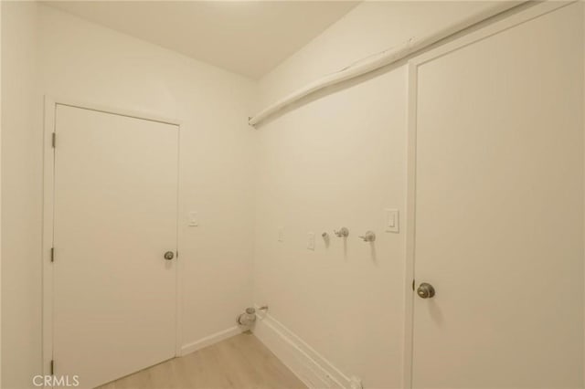 clothes washing area featuring baseboards, light wood-style floors, hookup for a washing machine, and laundry area