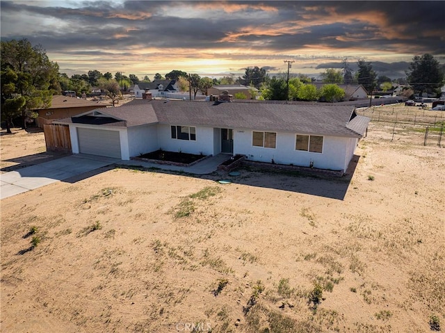 single story home featuring an attached garage, concrete driveway, and fence