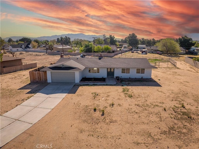 ranch-style house with a garage, stucco siding, fence, a mountain view, and concrete driveway